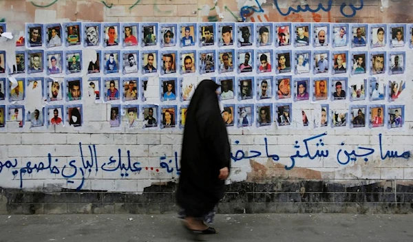 In this Oct. 22, 2015 file photo, a Bahraini woman walks past images of political prisoners plastered on a wall in Sanabis, Bahrain. (AP)