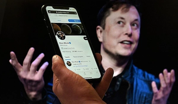 a phone screen displays the Twitter account of Elon Musk with a photo of him shown in the background, on April 14, 2022, in Washington, DC (AFP)