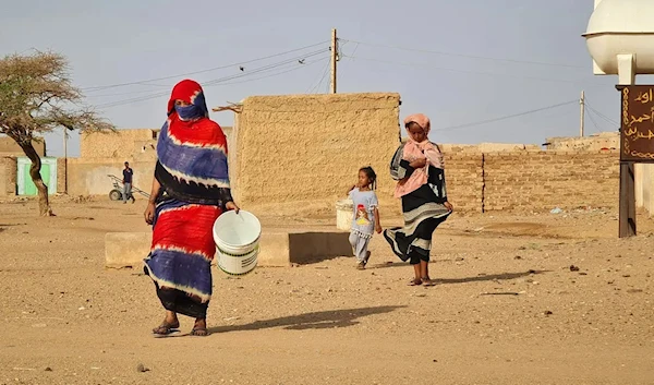 People carry buckets as they make their way to fill up on water in Omdurman on July 16, 2023, as fighting continues in war-torn Sudan. (Photo by AFP)