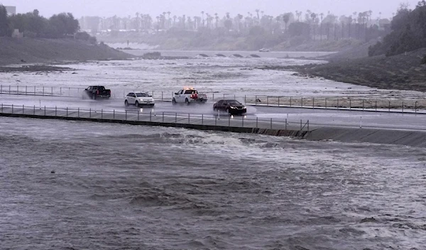 Cars are seen crossing over a flood control basin that has almost reached the street, Sunday, Aug. 20, 2023, in Palm Desert, California. (AP)