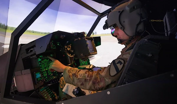 US Army aviator prepares for flight in an AH-64E Longbow Crew Trainer simulator at the Flight Simulation Division. (US Army)