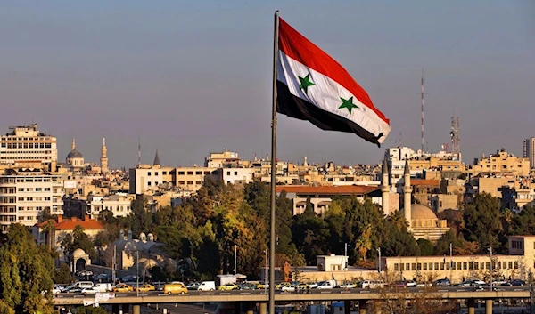 A Syrian national flag waves as vehicles move slowly on a bridge during rush hour, in Damascus, Syria, on Feb. 28, 2016. (AP)