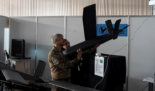 An exhibitor shows a drone to a visitor at iForum, an IT conference in Kiev, Ukraine, Thursday, August 10, 2023. (AP)