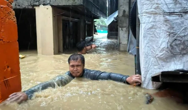 A man navigates through neck-deep floodwaters in his village caused by Typhoon Doksuri in Laoag city, Ilocos Norte province, northern Philippines, July 26, 2023. (AP)