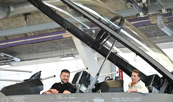 Ukrainian President Volodymyr Zelenskyy, left, and Danish Prime Minister Mette Frederiksen sit in a F-16 fighter jet in the hangar of the Skrydstrup Airbase in Vojens, northern Denmark, on Aug. 20, 2023 (AFP)