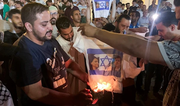 People burn a shirt showing Israeli Foreign Minister Eli Cohen and his Libyan counterpart Najla Mangoush in Tripoli, Libya, Sunday, Aug. 27, 2023. (AP)