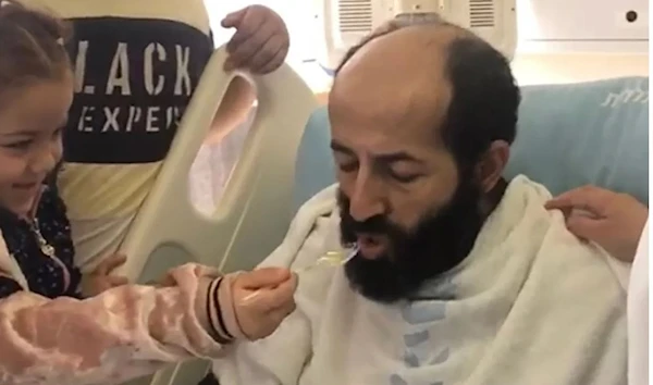 Maher al-Akhras is fed by his daughter Tuqa at a hospital in “Israel” on November 6 2020. (Courtesy Akhras Family)