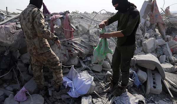 People look at a destroyed houses near the village of Barisha, in Idlib province, Syria, October 27, 2019 (AP)