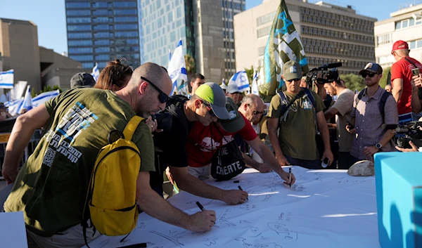 Israeli military reservists sign a declaration of refusal to report for duty to protest against plans by Prime Minister Benjamin Netanyahu's government to overhaul the judicial system, in 'Tel Aviv', occupied Palestine, July 19, 2023 (AP)