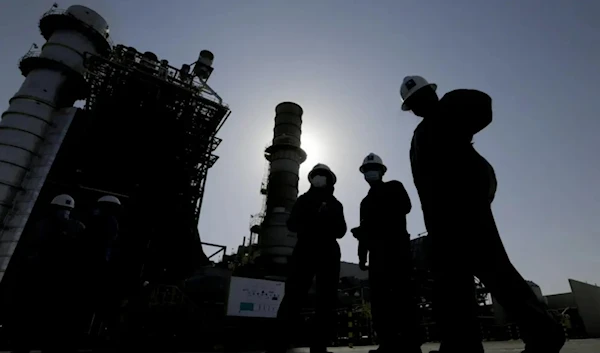 Saudi Aramco engineers walk in front of a gas turbine generator at Khurais oil field during a tour for journalists, 150 kilometers east-northeast of Riyadh, Saudi Arabia on June 28, 2021. (AP)