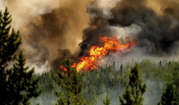 Flames from a wildfire along a ridge top north of Fort St. John, British Columbia, Canada, on July 2, 2023. (AP)