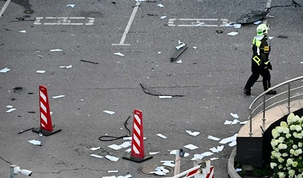 A firefighter walks among papers and broken glass outside a damaged office block of the Moscow International Business Center (Moskva City) following a reported drone attack in Moscow on July 30, 2023. (AFP)