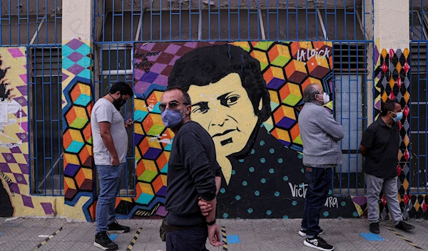 Voters line up in front a mural depicting portrait of Chilean songwriter Victor Jara, Santiago, Chile, Saturday, May 15, 2021 (AP)