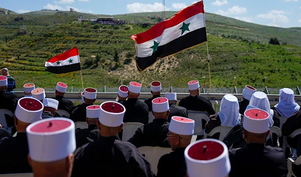 Druze men sit with Syrian flags during a rally marking Syria's Independence Day, in the Druze village of Majdal Shams in the Israeli-occupied Golan Heights, Syria, April 17, 2023 (AP)