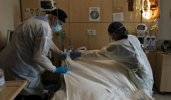 Respiratory therapist Frans Oudenaar, left, and registered nurse Bryan Hofilena cover a body of a COVID-19 patient with a sheet at Providence Holy Cross Medical Center in Los Angeles, Dec. 14, 2021. (AP)