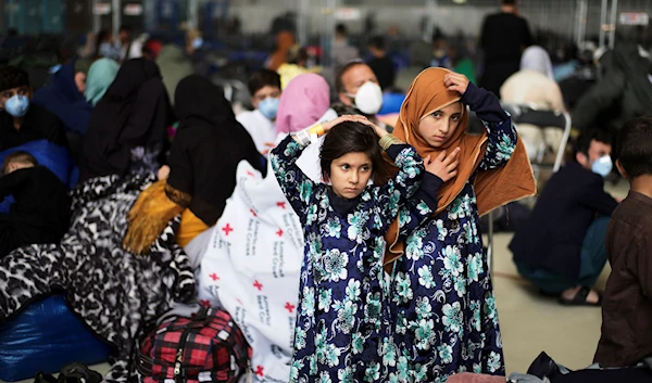 Two girls from Afghanistan wait with other evacuees to fly to the United States or another safe location in a makeshift gate inside a hanger at the U.S. Air Base in Ramstein, Germany, Wednesday, Sept. 1, 2021. (AP)