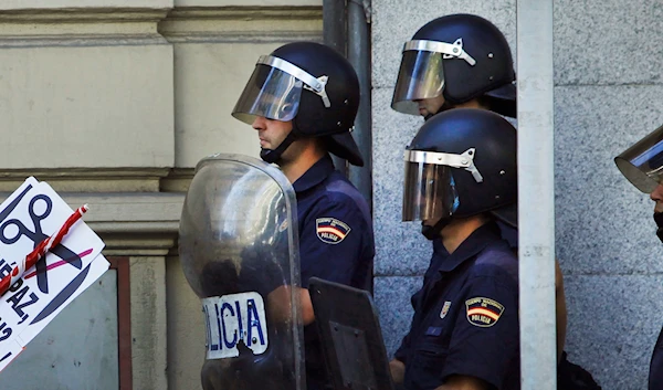 Police officers stand guard as people hold a banner reading "no bread, no peace" during a protest against austerity measures by the Spanish government in Columbus Square, Madrid, Spain, Saturday, Sept. 15, 2012. (AP)