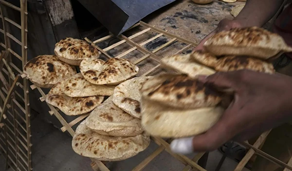 A worker collects Egyptian traditional 'baladi' flatbread at a bakery in el-Sharabia, Shubra district, Cairo. (AP)