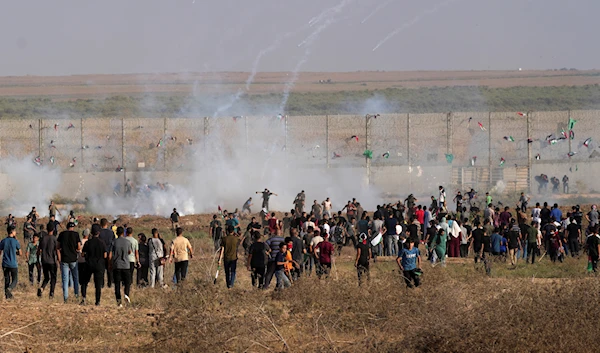 Palestinian protesters run to cover from tear gas during clashes with Israeli troops, along the frontier with Israel, east of Gaza City, Monday, Aug. 21, 2023 (AP Photo/Adel Hana)