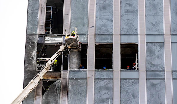 Workers clean a part of a damaged skyscraper in the "Moscow City" business district after a reported drone attack in Moscow, Russia, Wednesday, Aug. 23, 2023 (AP)