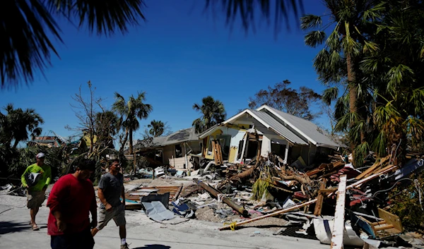 Men walk past destroyed homes and debris as they survey damage to other properties, two days after the passage of Hurricane Ian, in Fort Myers Beach, Fla., on Sept. 30, 2022. (AP)