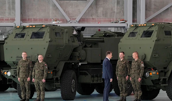 Polish Defense Minister Mariusz Blaszczak, third from right, talks to soldiers during a ceremony after receiving its first shipment of US-made HIMARS rocket launchers, at an air base in Warsaw, Poland, 15 May 2023 (AP)