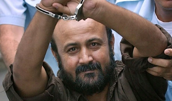 Palestinian Resistance leader Marwan al-Barghouti seen with his cuffed hands raised above his head flashing a peace sign during his trial in 2003. (AFP)