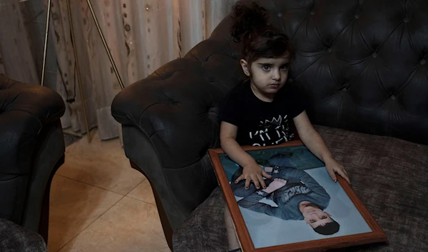 Sham Manasra holds a portrait of her older brother Ahmad Manasra, who has been imprisoned by 'Israel' since he was 13, in their family home in occupied Al-Quds, occupied Palestine Nov. 8, 2022 (AP)