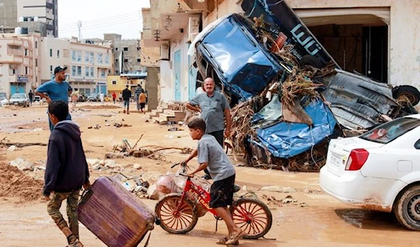 A boy pulls a suitcase past debris in a flash-flood damaged area in Derna, eastern Libya, on September 11, 2023. (AFP)