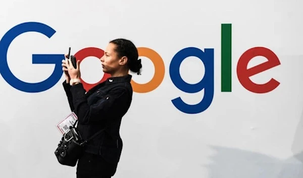 A woman using her phone in front of a Google sign. (AFP)