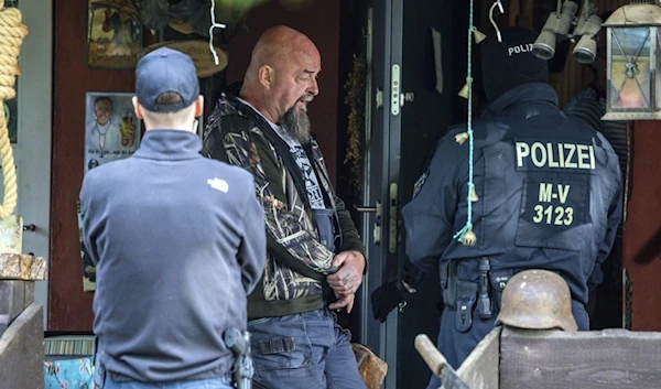 Sven Krueger, a right-wing extremist known throughout Germany, stands between police officers during a search operation on his property in Jamel, Germany, Sept. 19, 2023. (AP)