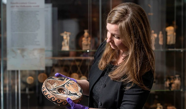 undated handout photo published on September 15, 2023 by the Australian National University (ANU) in Canberra shows ANU Museum curator Georgia Pike-Rowney holding a red Apulian fish plate (AFP)