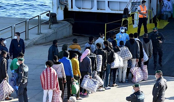 Migrants queue before boarding the GNV Azzurra ship after being transferred from the migrant center on the Sicilian island of Lampedusa, May 13, 2021. (AP)