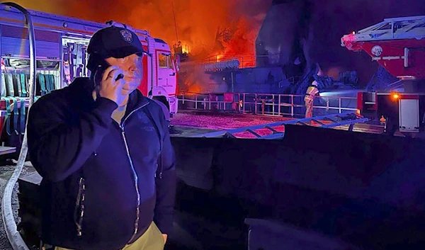 The Governor of Sevastopol, Mikhail Razvozhaev, is seen speaking on a phone as smoke and flame rise from a burning shipyard in Crimea in this photo posted to Razvozhaev's Telegram channel on Sept. 13, 2023. (AP)