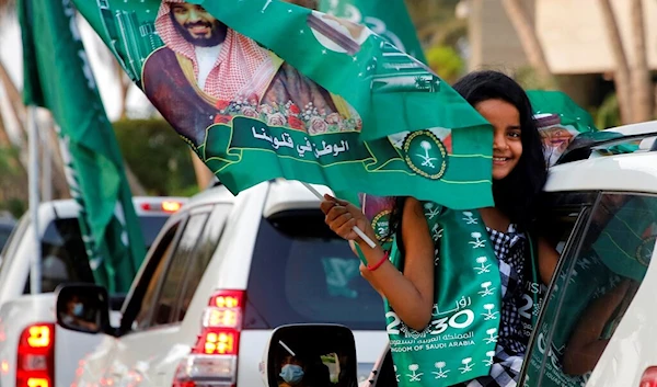 A Saudi girl waves a national flag with the picture of Saudi Crown Prince Mohammed bin Salman during celebrations marking National Day,  September 23, 2020 (AP)