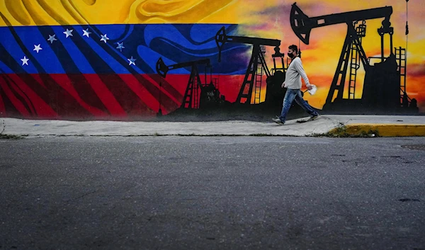 A man walks past a mural featuring oil pumps and wells in Caracas, Venezuela, Saturday, May 21, 2022. (AP)