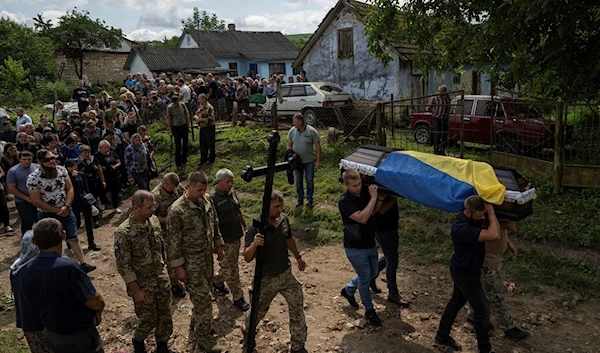 People carry the coffin of Ukrainian serviceman Bohdan Kobylianskyi who was killed in Donbas, during a funeral ceremony in Dusaniv, Ukraine, Saturday, July 22, 2023 (AP)