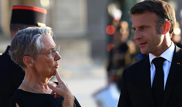 French President Emmanuel Macron listens to French Prime Minister Elisabeth Borne outside the Louvre museum before a dinner, in Paris, Friday, July 14, 2023 (AP)