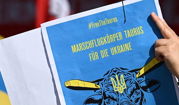 A supporter of Ukraine holds up a placard calling on the German government to supply Ukraine with Taurus missiles in Munich, Germany (AFP)