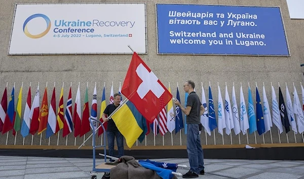 Staff members of the Swiss confederation prepare the flags of Ukraine and Switzerland, ahead of the Ukraine Recovery Conference in Lugano, Switzerland, 3 July 2022 (AFP)