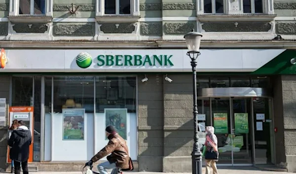 A man cycles past a Ljubljana, Slovenian branch of the Russian state-owned bank, Sberbank, on February 28, 2022. [AFP]