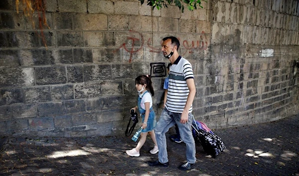 A man walks with his children at the end of their school day in Beirut, Lebanon, Wednesday, Sept. 29, 2021 (AP Photo/Bilal Hussein)