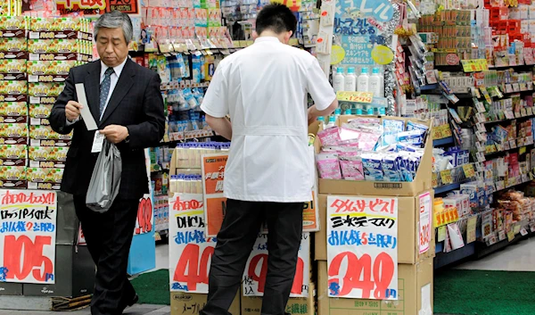 A businessman checks his receipt after shopping at a discount store in Tokyo, Monday, Feb. 14, 2011. (AP)