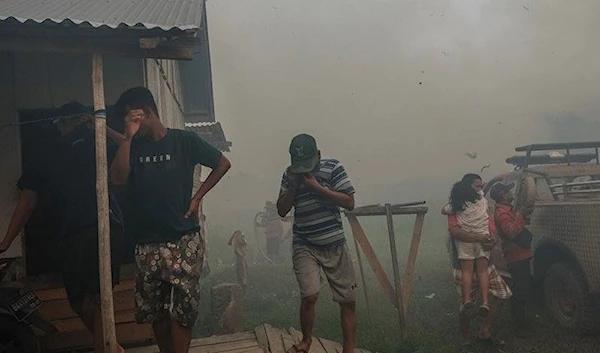 People react amidst smoke as firefighters try to protect houses from a wildfire in Ogan Ilir, South Sumatra, on Sept. 27, 2023. (AFP)