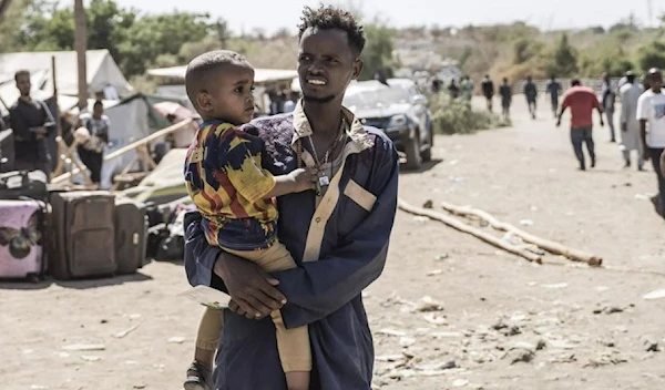 A man carries a child at the border town of Metema, the crossing point for thousands fleeing from Sudan into Ethiopia. (AFP)