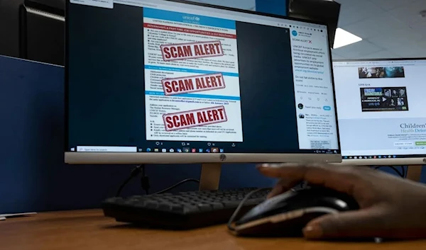 A man in an undated photo showing a sign saying 'scam alert' on a computer screen (AFP)