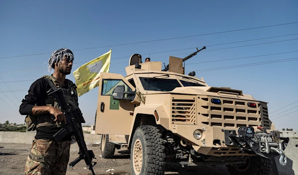 A US-backed Syrian Democratic Forces (SDF) fighter stands next an armored vehicle, at al-Sabha town in the eastern countryside of Deir Ezzor, Syria, Sept. 4, 2023 (AP)