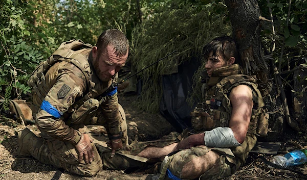 A soldier of Ukraine's 3rd Separate Assault Brigade gives first aid to a wounded soldier near Bakhmut, the site of fierce battles with the Russian forces in Donetsk, Sept. 4, 2023 (AP)