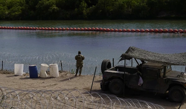 A guardsman keeps watch over a section of the Rio Grande that is fortified with concertina wires and large buoys being used as a floating border barrier. (AP)