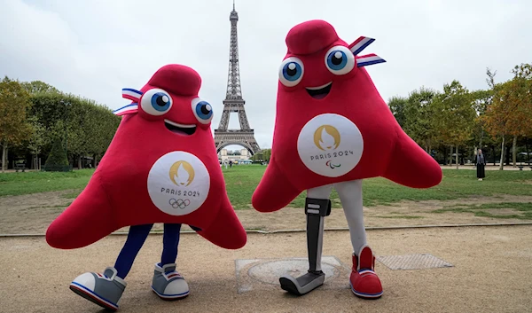 The mascots of the Paris 2024 Olympic, left, and Paralympic Games pose next to the Eiffel Tower in Paris, August 28, 2023 (AP)